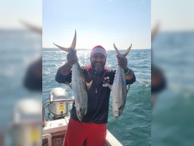 A proud angler displays his impressive catch while fishing on a boat, showcasing the thrill of a successful day on the water.