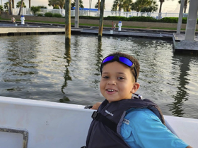 A cheerful child enjoys a moment on a boat at the marina, showcasing the joy of family outings on the water.