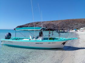 A vibrant speedboat named 'Mi Niño' docked in the clear waters of La Paz, B.C.S., showcasing a perfect day for fishing or leisure on the beach.