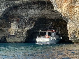 A scenic view of a boat docked inside a cave, showcasing the unique geological formations and tranquil waters — perfect for exploring hidden gems on the coast.