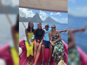 A joyful family poses together on a boat with stunning island scenery in the background, perfect for memorable adventures on the water.