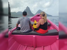 A couple enjoys a scenic boat ride with stunning mountain views in the background, perfect for exploring the beauty of the coastline.