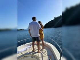 A couple enjoys a romantic moment on the bow of a boat, surrounded by serene waters and scenic views — perfect for memorable getaways.