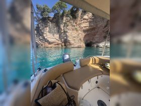 A cozy interior view of a boat's seating area, showcasing the inviting space perfect for relaxation while enjoying the stunning coastal scenery.