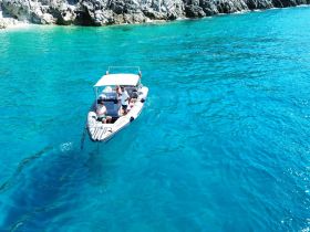 A group enjoys a day on the water aboard a boat, surrounded by stunning turquoise waters and rocky shores — perfect for adventure and exploration.