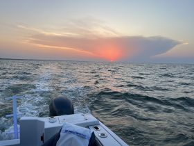 A serene sunset view from a boat, showcasing the tranquil waters and vibrant sky — perfect for evening cruises.
