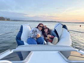 Two friends enjoy cocktails while relaxing on the deck of a boat at sunset, capturing the essence of a perfect day on the water.