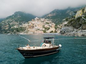 A scenic view of a boat near the picturesque coastline of Positano, capturing the essence of a relaxing day on the water amidst stunning Italian architecture.