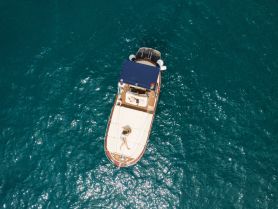 Aerial view of a boat cruising through clear turquoise waters, showcasing its sleek design and inviting atmosphere for a perfect day on the water.