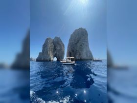 A picturesque view of boats near the iconic rock formations, showcasing the stunning coastline and vibrant blue waters — a perfect destination for boating adventures.