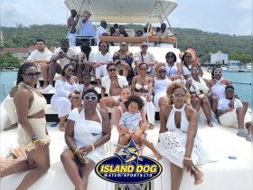 A vibrant group of friends and family enjoy a boat party, showcasing a joyful celebration on the water with stunning views in the background.