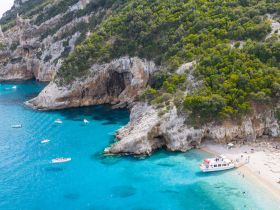 A stunning aerial view of a secluded beach with boats anchored in turquoise waters, showcasing a perfect destination for relaxation and water activities.