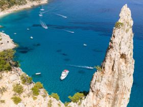 A stunning aerial view of a serene coastline with multiple boats navigating the crystal-clear waters, showcasing the beauty of the landscape and perfect for exploring hidden beaches.