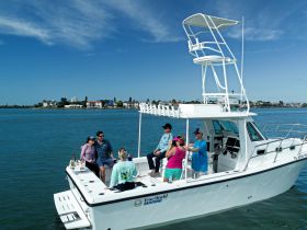 A lively group enjoys their time aboard a boat, perfect for celebrations and fun on the water, with a beautiful waterfront backdrop.