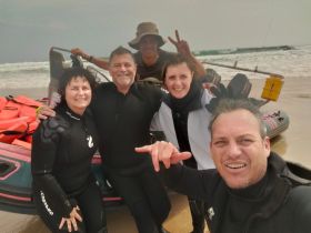 A cheerful group poses for a selfie on the beach after an exciting water activity, showcasing the fun and camaraderie of their adventure.
