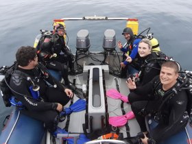 A group of divers prepares for an underwater adventure, showcasing camaraderie and excitement aboard their diving boat.