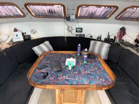 Interior view of a cozy boat cabin featuring a dining area with seating and various items on the table, perfect for relaxing and enjoying meals while on the water.