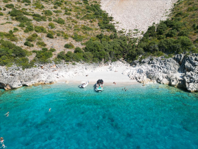 A vibrant scene of guests enjoying a sunny day at the beach, with boats anchored in the turquoise waters — perfect for swimming and relaxation.