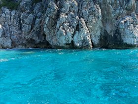 An unclear image of rocky cliffs beside turquoise waters, lacking identifiable features or subjects.