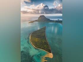 A stunning aerial view of a lush island surrounded by turquoise waters, showcasing the natural beauty of the coastline — perfect for eco tours and island hopping adventures.