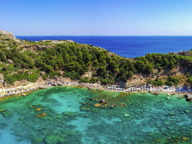 A stunning aerial view of a secluded beach with crystal-clear turquoise waters and lush greenery, perfect for a relaxing getaway or island exploration.