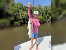 A young angler proudly displays his catch while fishing from a boat, showcasing the joy of outdoor adventures and family fishing trips.