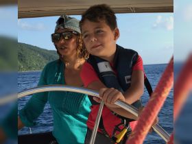 A joyful moment on the water as a child and an adult navigate a boat together, showcasing the fun of family sailing adventures.