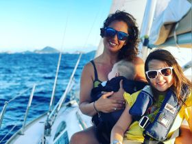 A joyful family enjoys a sailing adventure on the ocean, with children wearing life jackets and soaking in the beautiful maritime experience.