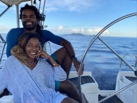 A joyful couple enjoys a sailing experience on the open ocean, capturing a moment of happiness and adventure aboard their boat.
