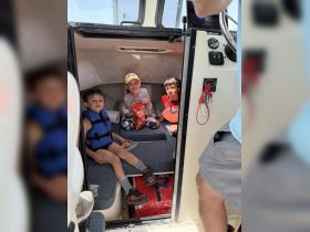 Three children enjoy snacks in the cozy cabin of a boat, showcasing a fun and safe environment for young guests.