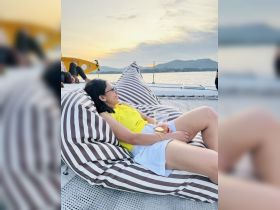 A woman enjoys a relaxing moment on a boat, sipping a cocktail as the sun sets in the background — perfect for unwinding with friends on the water.
