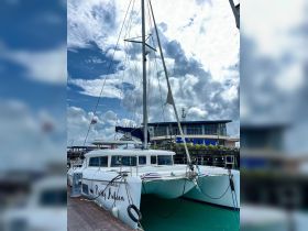 A stunning view of the catamaran 'Pretty Aileen' docked at the marina, showcasing its sleek design against a backdrop of dramatic clouds.