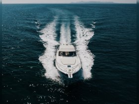 A stunning aerial view of a sleek speedboat cruising through deep blue waters, showcasing the vessel's design and performance.