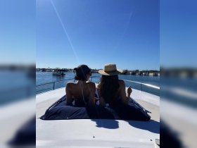 Two friends enjoy a sunny day on a boat, taking in the beautiful water views — a perfect moment for relaxation and fun on the water.