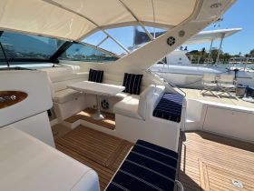 A stylish interior view of a boat's lounge area featuring comfortable seating and a table, perfect for relaxing or entertaining guests while on the water.