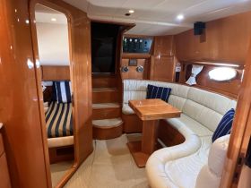 Interior view of a yacht's cabin featuring comfortable seating and a well-equipped helm area, perfect for relaxing during a cruise.