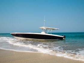 A sleek speedboat rests on the shore, showcasing its elegant design against a backdrop of clear blue skies and gentle waves — perfect for a day of adventure on the water.