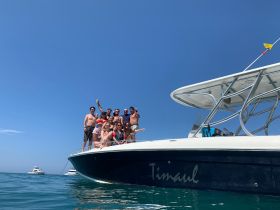 A lively group of friends celebrates on the bow of a boat, enjoying a sunny day on the water — perfect for summer outings and memorable gatherings.