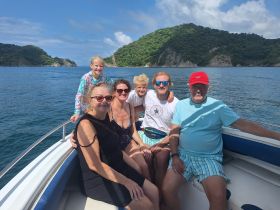 A joyful family poses together on a boat, surrounded by stunning coastal scenery — perfect for memorable outings and adventures on the water.