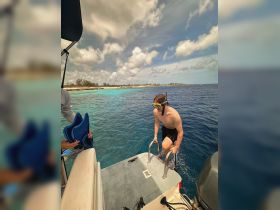 A young snorkeler prepares to dive into the clear blue waters from a boat, showcasing the excitement of underwater exploration and adventure.