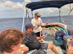 A group aboard a boat receives snorkeling instructions, showcasing the excitement of a day on the water with friends and family.