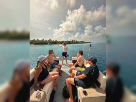 A group of friends enjoys a scenic boat tour, with one person pointing out interesting sights along the beautiful turquoise waters.