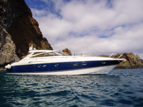 A stunning side view of a luxurious yacht anchored near rocky cliffs, showcasing the perfect blend of elegance and nature's beauty.