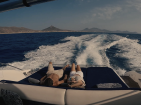 A couple relaxes on the deck of a boat, enjoying the scenic views and the open water — a perfect moment for a romantic getaway.