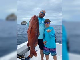 A proud moment as a father and son display their impressive catch while fishing together — a perfect family adventure on the water.