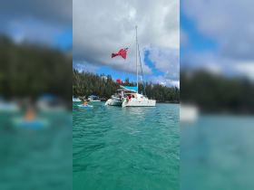 A lively scene featuring a catamaran anchored in turquoise waters, with guests enjoying swimming and relaxation — perfect for a fun day on the water.