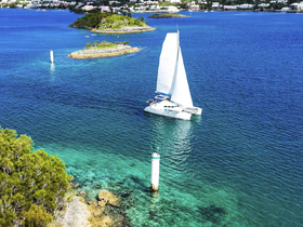 A stunning aerial view of a catamaran sailing through crystal-clear waters, surrounded by lush islands — perfect for showcasing the beauty of boating adventures.