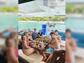 A lively group enjoys a delicious meal aboard a catamaran, showcasing the perfect blend of dining and camaraderie on the water.