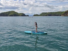 A woman paddleboards in serene waters surrounded by lush islands, showcasing the beauty of outdoor water activities.