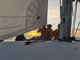 A group enjoys a stunning sunset while sailing, creating a perfect backdrop for memorable moments on the water.